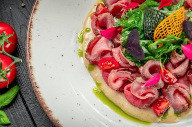 Renkli bir tabakta servis edilen lezzetli et ve sebzeler. Biftek dilimleri yeşil ve renkli malzemelerle servis edilir..