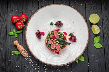 Taze ton balıklı salata, beyaz bir tabakta sebze ve otlarla servis ediliyor. Ton balığı, sebze ve otlardan yapılmış bir salata beyaz bir tabağa konur..