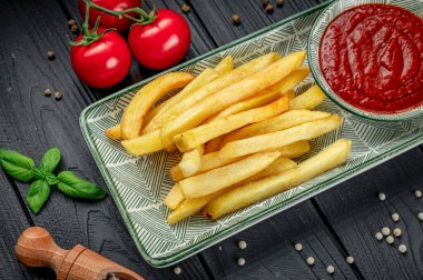 Patates kızartması ve ketçapla servis edilen domates ve otlar..