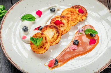 Lokantada beyaz tabakta yaban mersinli ve nane şekerli lezzetli bir tatlı. Lokantada servis edilen tatlı, beyaz bir tabakta böğürtlen ve nane şekerli tatlı içerir..