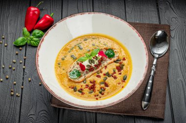 Bir kase çorba, kırmızı biber ve taze otların yanına ahşap bir masanın üzerine konur. Bir kase çorba ahşap bir masaya konur kırmızı biber ve taze otların yanına..