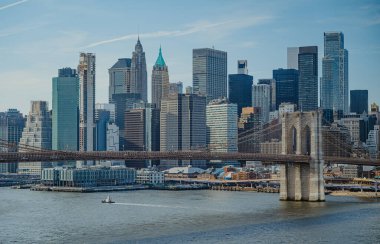 Brooklyn Köprüsü ve şehrin ufuk çizgisi, gün ışığında denizde tekneler. Sahne Brooklyn Köprüsü 'nü gösteriyor. Suda tekneleri ve şehirde gündüz binaları var..