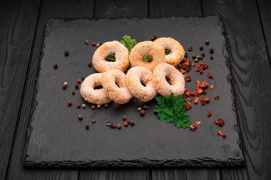 Baharat ve otlarla dolu siyah taş bir tabakta taze pişmiş çörekler. Çörekler taştan bir tabağa konur. Renkli baharatlar ve bitkiler her yeri sarmış..