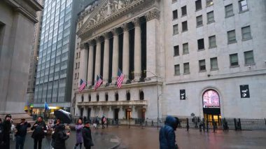 New York, ABD, 28 Aralık 2025: İnsanlar yağmurlu bir günde New York Borsası 'nın önünde toplanıyor. İnsanlar hafif yağmurda ellerinde şemsiyelerle New York Borsası 'nın yanında durup fotoğraf çekiyorlar..