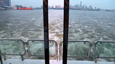 Feribottan New York ufuk çizgisine bak. Feribotun arkasında uyan. New York City 'nin ufuk çizgisi suyun üzerinde..