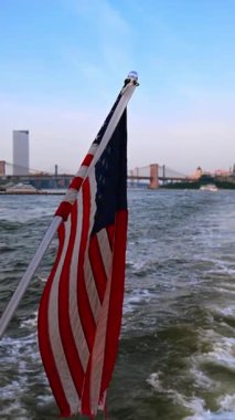 Nehir kıyısında Amerikan bayrağı ve köprüler. Köpüklü bir feribotta Amerikan bayrağı New York köprülerine doğru ilerliyor..