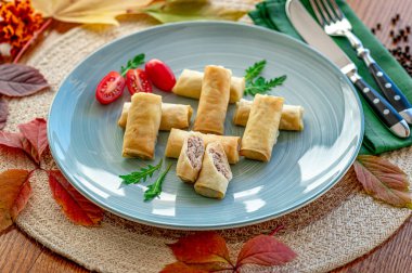 Sonbahar yaprakları ve çatal bıçaklarla çevrili mavi bir tabakta tuzlu atıştırmalıklar. Atıştırmalıklar mavi bir tabakta, yanında taze domates ve yapraklarla hazırlanır..