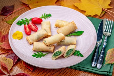 Yumurtalı börekler yeşil yapraklar ve vişneli domateslerle yuvarlak bir tabağa konur. Yumurtalı börekler yeşil yapraklar ve kiraz domatesleriyle yuvarlak bir tabağa konur..