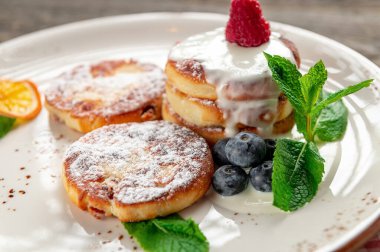 Kremalı krep ve beyaz tabakta servis edilen meyveler. Kremalı ve taze meyveli krepler bir tabakta duruyor. Nane yaprakları renk ve tazelik ekler.