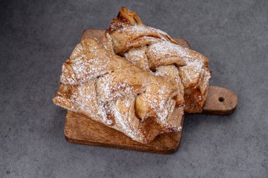 Sıcak hamur işleri tahtanın üzerinde, üzerinde pudra şekeri olan bir tahtanın üzerinde oturur. Ahşap bir tahtaya iki fırında hamur işi konur..