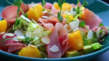 Taze salata, karışık sebzeler, etler ve bir kasede servis edilen meyveler. Bir kase içinde salata, marul, et, meyve ve fındık var..