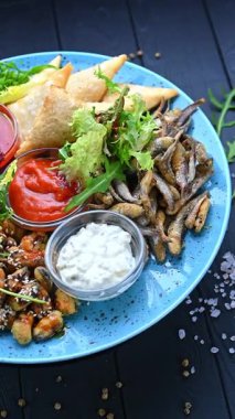 Öğle ya da akşam yemeği için çeşitli tabak ve soslarla nefis yemek tabağı. İçinde balık, samosa, sos ve salata olan renkli bir tabak hazır..