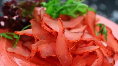 Marul ve garnitürle bir tabakta hazırlanmış et dilimleri. Kırmızı et dilimleri düzgün bir şekilde taze yeşilliklerin yanına, pembe bir tabağa yerleştirilir..