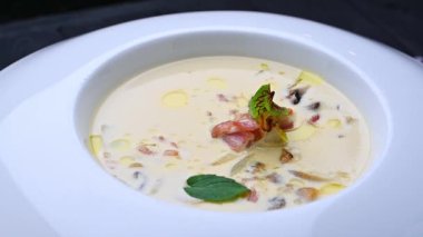 Restoranda beyaz bir kasede servis edilen sebzeli ve şifalı kremalı çorba. Kremalı çorba, sebzeler ve şifalı otlarla beyaz bir kasede hazırlanır..