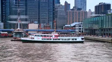 Manhattan rıhtımında bir feribot. Daire çizgisi gezisi feribotu Manhattan limanı boyunca kentin arkasında binalar var..