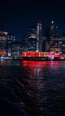 Manhattan 'ın alt ufuk çizgisi gece kıyısı. Parlak rıhtım ışıkları, Manhattan 'ın alt ufuk çizgisini aydınlatıyor..