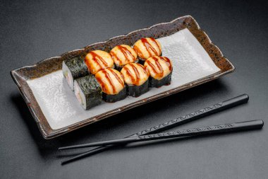 Restoranda bir tabakta servis edilen soslu suşi ruloları. Suşi dürümleri bir restoranda yemek masasında soslu bir tabağa konur..