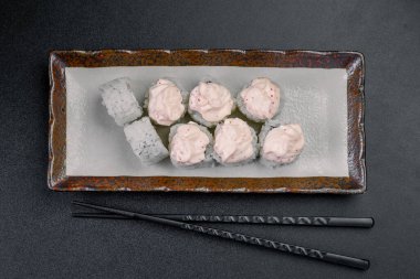 Yanında çubuklar olan bir tabakta pembe soslu suşi ruloları. Bir tabakta pembe soslu bir kaç suşi rulosu var..