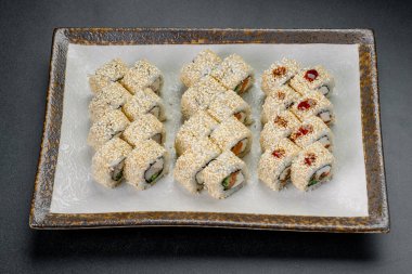 Suşi ruloları bir restoranda susam tohumlarıyla servis edilir. Suşi ruloları düzgün bir tabakta dizilir..