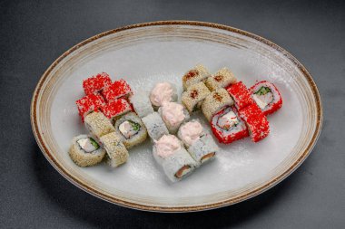 Suşi dürümleri öğle yemeği vakti bir restoranda bir tabağa yerleştirilmiş. Öğle yemeği sırasında bir suşi restoranında çeşitli suşi ruloları beyaz bir tabakta sergilenir..