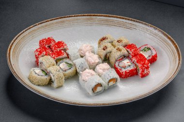 Suşi ruloları, bir restoranda öğle yemeği için yuvarlak bir tabağa dizilmiş. Bir restoranda farklı suşi ruloları yuvarlak bir tabağa konur..