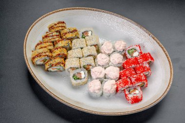 Restoran ortamında yuvarlak bir tabakta servis edilen farklı suşi türleri. Suşi ruloları renkli bir sunumla yuvarlak bir tabakta düzenlenir..