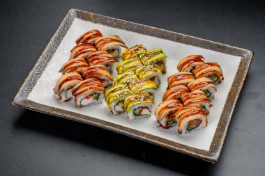 Yemek için farklı malzemeler ve malzemelerle hazırlanmış suşi ruloları. Farklı malzemeler ve soslarla birlikte bir tabak dolusu suşi..