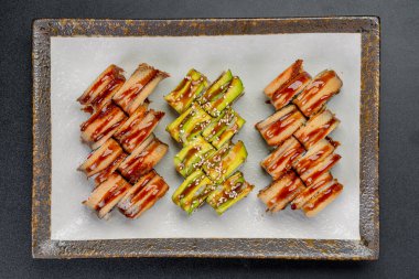 Restoranda farklı soslar ve malzemelerle hazırlanmış bir tabak suşi. Suşi bir restoranda bir tabakta oturur..