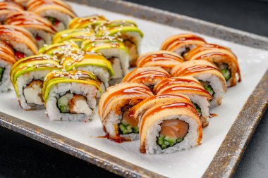 Suşi ruloları yemek sırasında bir tepside dizilmiş. Birkaç renkli suşi rulosu bir tepside öğle yemeği için hazır olarak sergilenir..