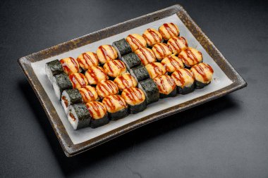 Suşi ruloları dikdörtgen bir tabakta bir yemekte servis edilmeye hazır. Çeşitli suşi ruloları dikdörtgen bir tabağa yerleştirilir..