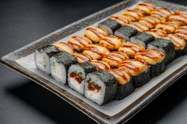 Suşi ruloları yemek saatinde bir restoranda servis edilir. Akşam bir restoranda müşteriler için iki çeşit suşi rulosu bir tabağa konur..