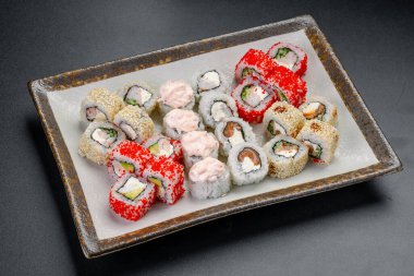 Yemek sırasında farklı türde suşi dürümleri servis edilir. Suşi börekleri ve çeşitli malzemeler öğle yemeği ya da akşam yemeği için bir tabağa dizilmiş..