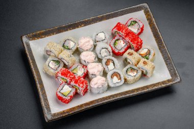 Suşi bir restoranda çeşitli ekmeklerle servis edilir. Bir tabakta çeşitli suşi türleri düzenlenir, renkli rulo ve küçük porsiyonlar gösterilir..