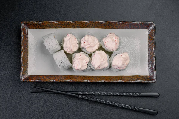 Yanında çubuklar olan bir tabakta pembe soslu suşi ruloları. Bir tabakta pembe soslu bir kaç suşi rulosu var..