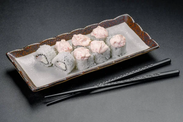 Yengeçli suşi ruloları ve yemek çubuklarıyla servis edilen baharatlı mayonez. Taze suşi ruloları yemek çubuklarının olduğu bir tabağa konur..