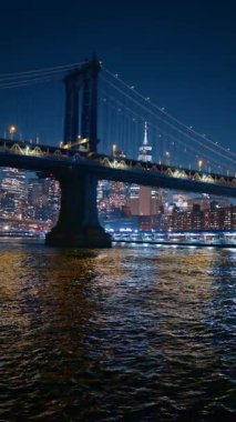 Manhattan Köprüsü ve New York gökyüzü geceleri. Aydınlatılmış köprünün ve Tek Dünya Ticaret 'in suyundan görüntü