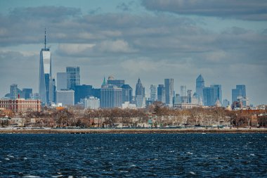 Manhattan 'ın alt ufuk çizgisinin detaylı görüntüsü ve bulutlu bir gökyüzü arka planına sahip bir Dünya Ticaret Merkezi..