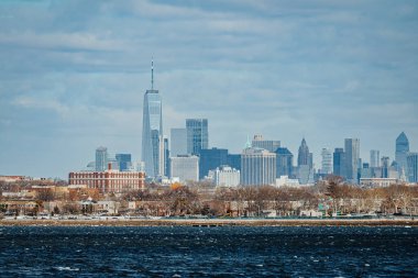 New York şehrinin gökyüzü bulutlu gökdelenlerin altında Dünya Ticaret Merkezi ve finans bölgesi gökdelenlerinin yer aldığı uzun bir görüntüsü.