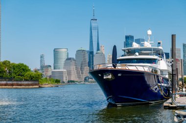 Manhattan gökdelenlerinin ve gökdelenlerin yer aldığı ahşap bir rıhtımda büyük mavi bir yatın yan görüntüsü.