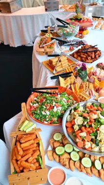 Aperatifler ve abur cuburlarla dolu büyük bir ziyafet masası. Salata dolu uzun bir masa. Kızarmış atıştırmalıklar ve et tabakları.