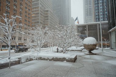 New York, ABD, 20 Şubat 2026: Manhattan şehir merkezindeki metal küre heykelini kar kapladı. Büyük küresel bir heykel ve ağaçlar New York kış tipi sırasında kalın beyaz karla kaplıdır..