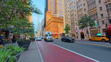 New York, ABD, 9 Ağustos 2025: Manhattan Caddesi 'nde gökdelenleri olan beyaz teslimat kamyonu. Beyaz bir kamyon, Amerikan bayrakları ve New York 'ta uzun bir mimarinin yer aldığı şehir trafik sahnesi