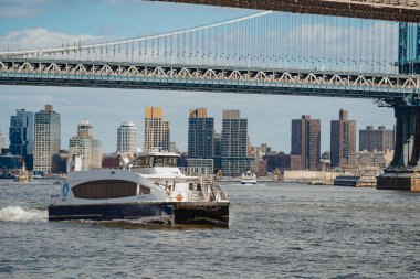Manhattan Köprüsü 'nün altından East River' a giden bir feribot. Nehirde mavi ve beyaz bir tekne... Ufuk çizgisi ve asma köprüsü olan...