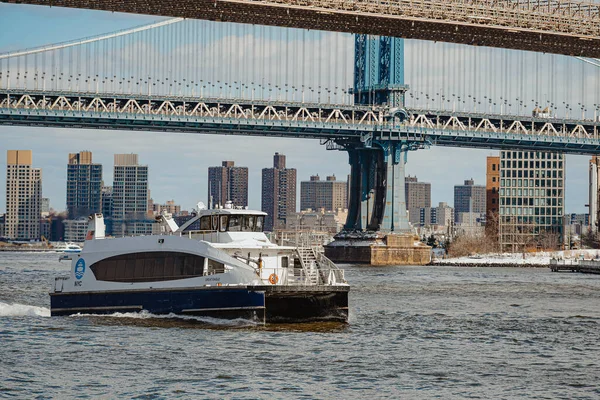 Manhattan Köprüsü yakınlarındaki East River 'dan yolcu feribotu kalkıyor. Köprü ve şehrin ufuk çizgisi arka planında suda hareket eden bir tekne.