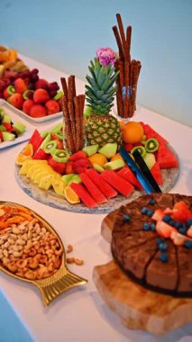 Ziyafet masasında dilimlenmiş tropik meyve ve çubuk kraker. Yemek servisi için beyaz tabaklara yerleştirilmiş kivi, ananas, karpuz, üzüm ve kraker yakın plan..