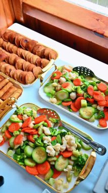 Tepsiler dolusu kızarmış börek ve buharda pişirilmiş sebze. Altın hamur işleri, börek, brokoli, havuç, kabak ve karnabahar ile servis tabakları..