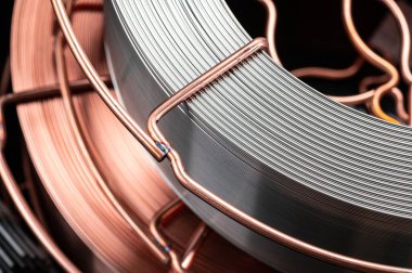 Bakır ve çelik kaynak kablosu kapanıyor. Endüstriyel makaralarda bakır kaplama ve gümüş kaplama ile boyanmış metal kaynak kablosu ayrıntılı görünümü.