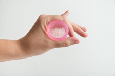 El, beyaz arka planda adet bardağını tutuyor.