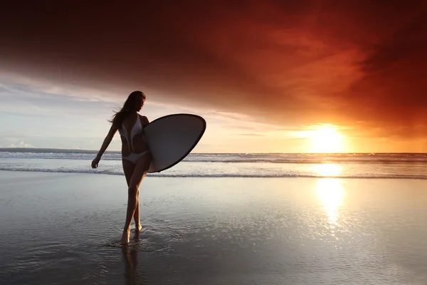 Surfista mulher na praia ao pôr do sol — Fotografia de Stock