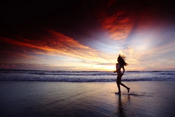 Femme courant sur la plage au coucher du soleil — Photo